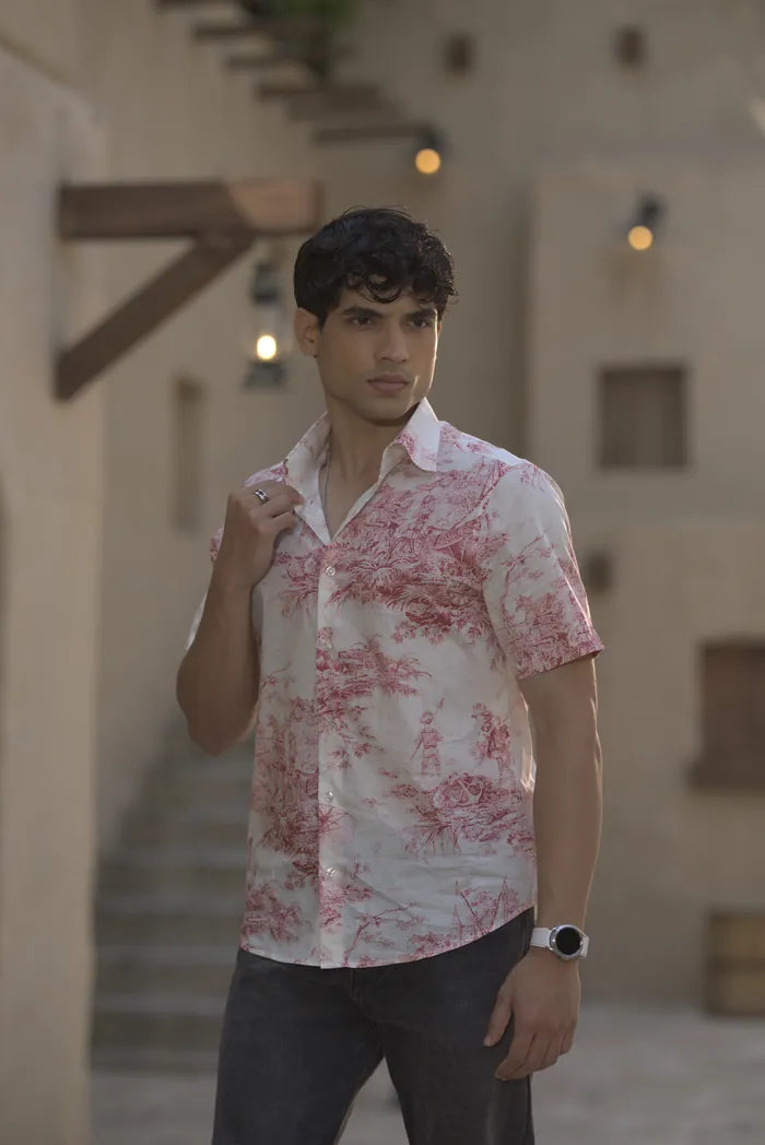 A model in a short-sleeve shirt with a red toile print, in a sandstone courtyard