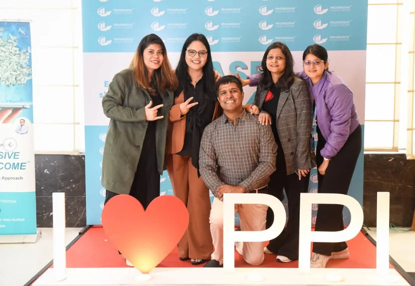 Five attendees posing in front of a lit I love PPI sign at a BASE event