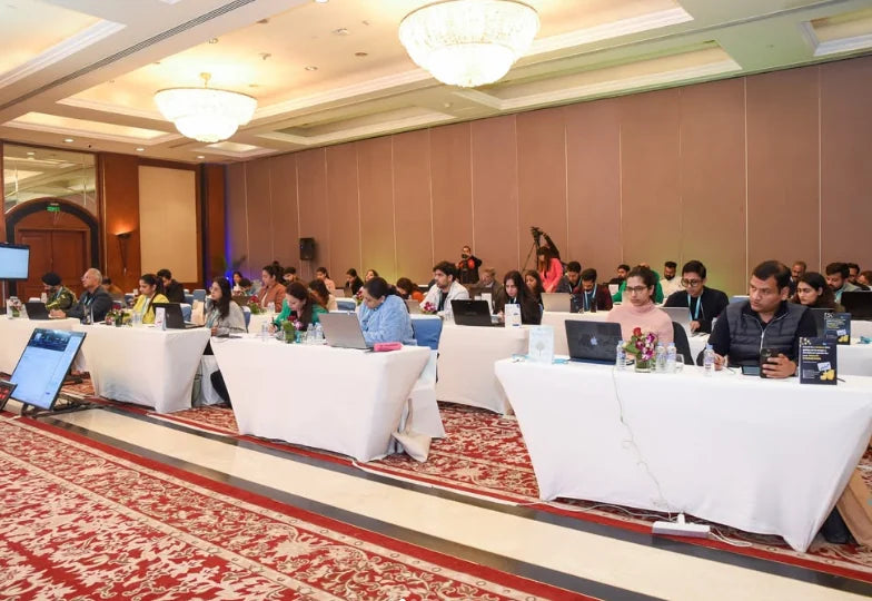 Attendees seated at tables with laptops in a hotel conference room