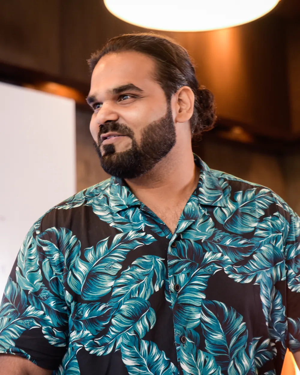 Gaurikant Dhingra, Account Director, looking to one side at an event, in a leaf-print shirt