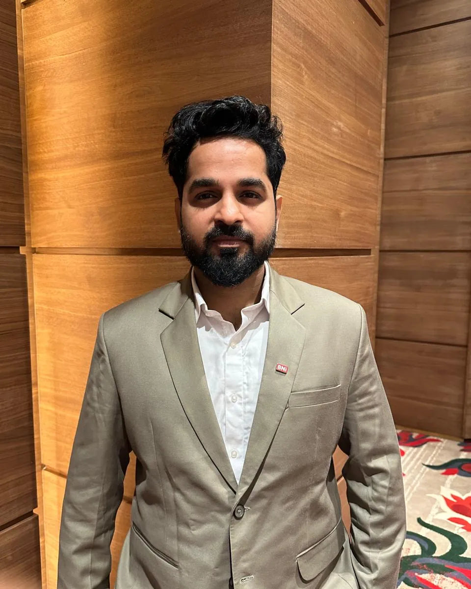 Portrait of Rajnikant Dhingra, Digital Business Manager, in a beige suit in front of wood panelling