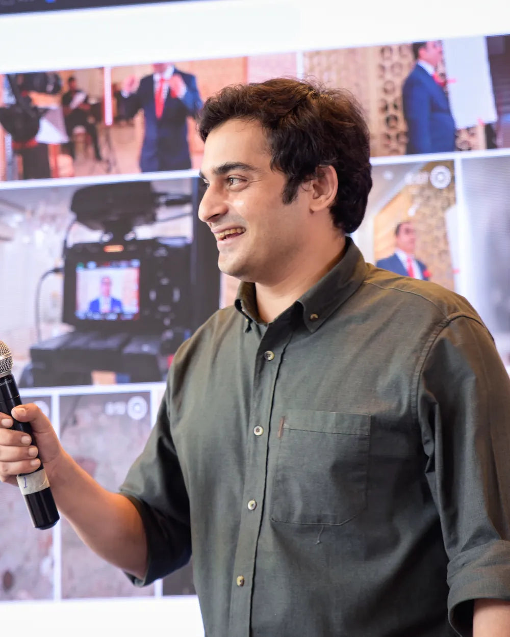 Udit Sharma, Video Producer, speaking into a microphone in front of a projected screen